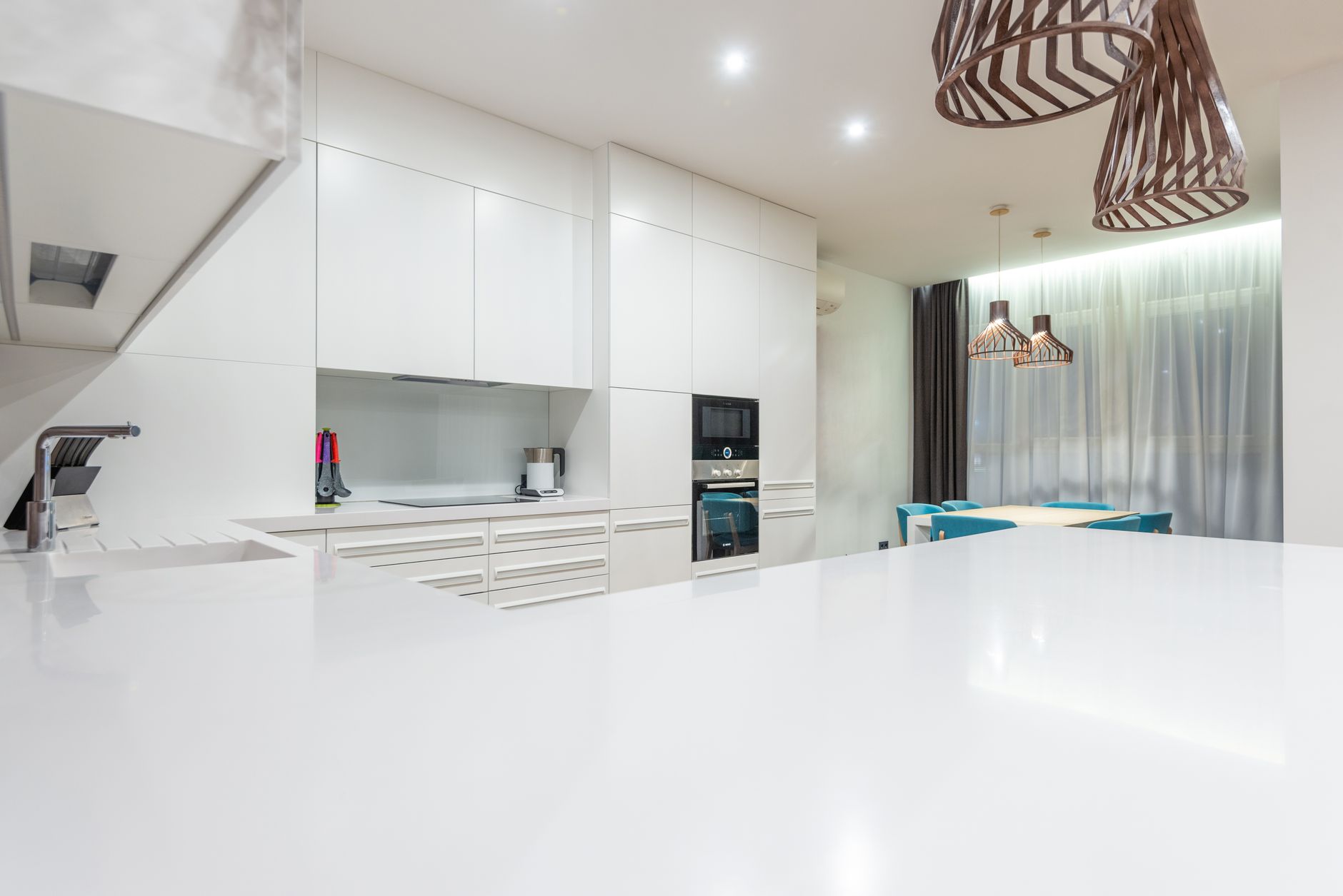 Empty kitchen counter against white cupboards and modern appliances near chairs at table placed near window in Austin, TX