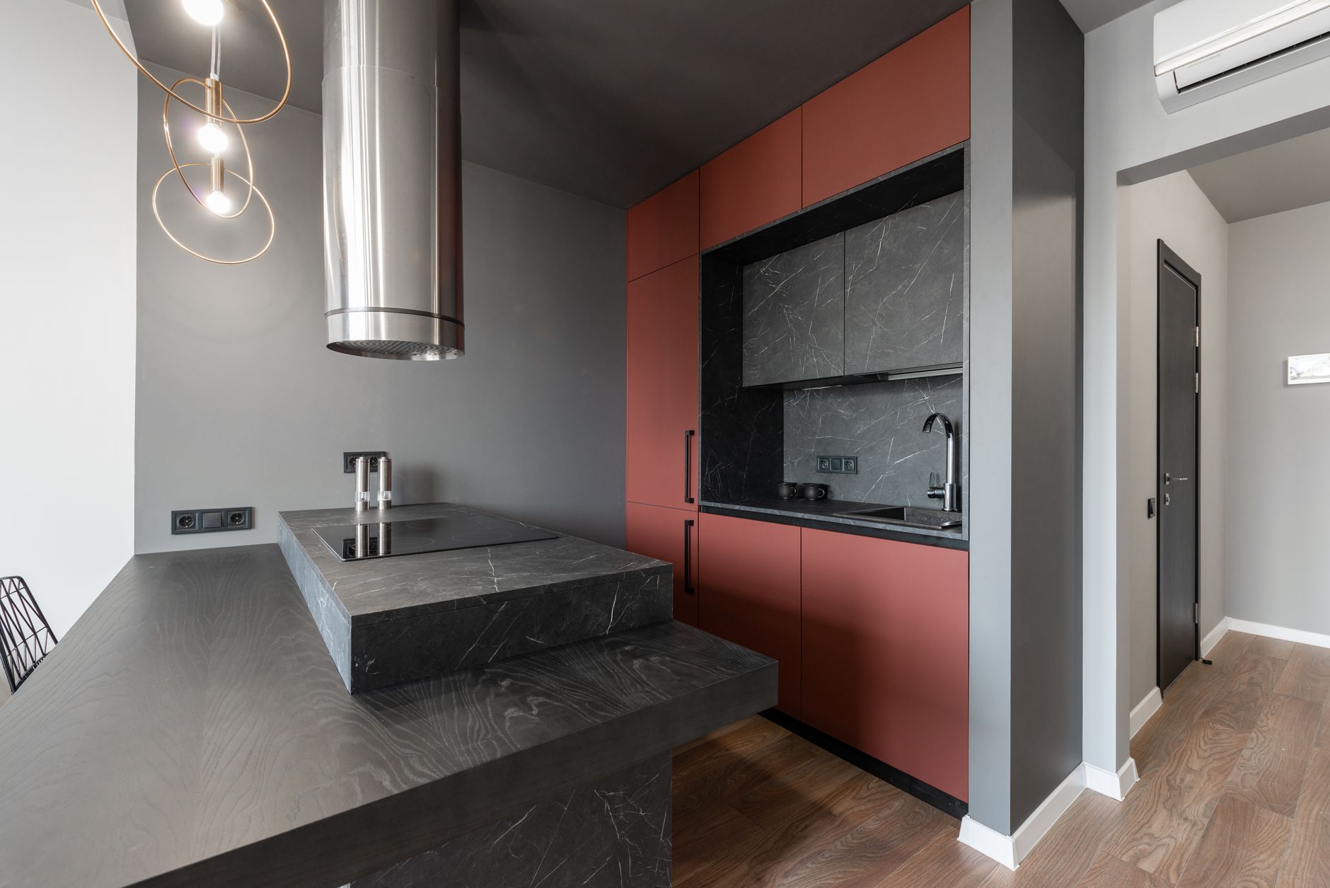 Contemporary minimalist island style kitchen with metal tube range hood over counter with built in stove in in Austin, TX